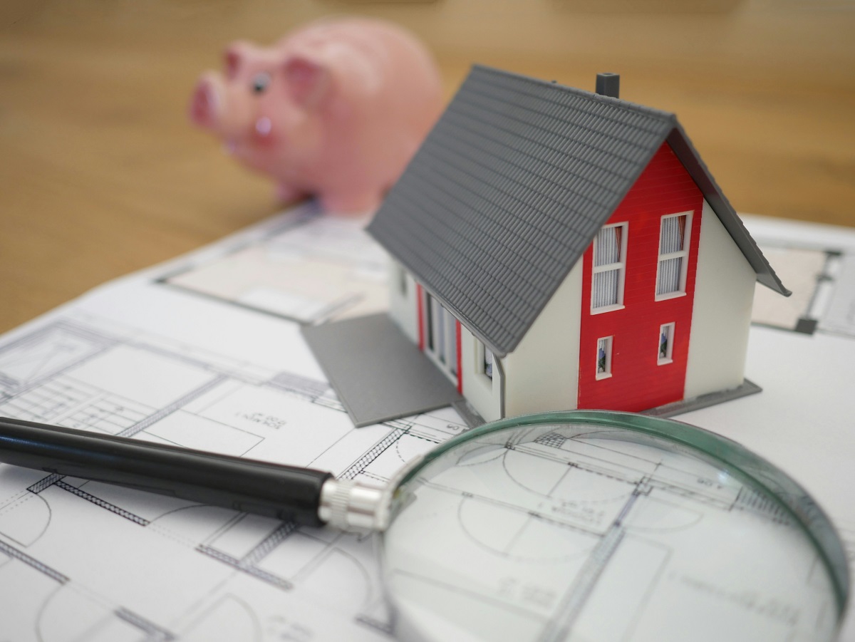 blueprint, magnifying glass, miniature house, and piggy bank